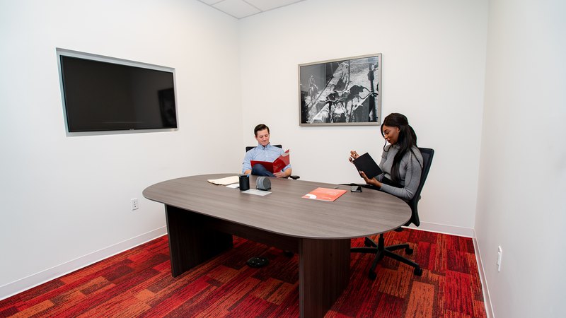 Two workers collaborating in a meeting room at a coworking location.